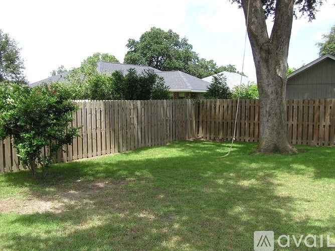 A backyard with a wooden fence and a tree.