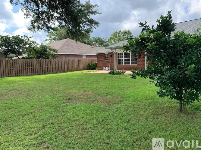 A backyard with a fence and a house in the background.