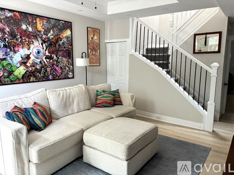 A living room with a white couch and a large painting on the wall.