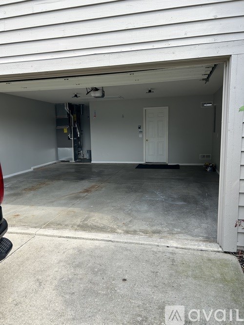 A white garage door is open to reveal a clean, empty garage.