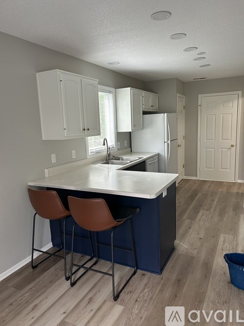 A kitchen with a blue island and brown chairs.