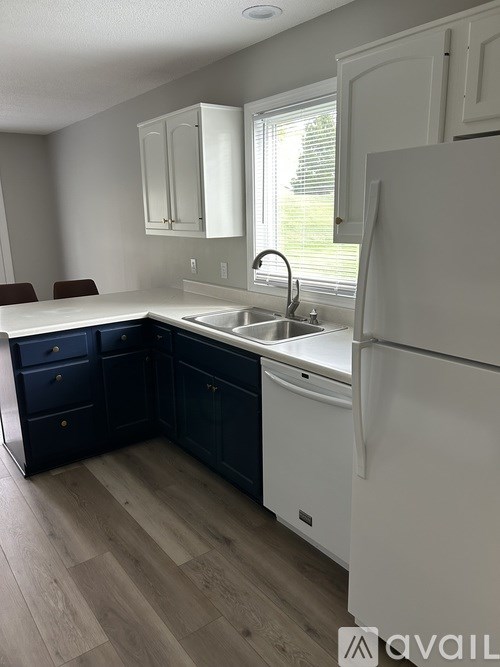 A kitchen with a white refrigerator, sink, and cabinets.