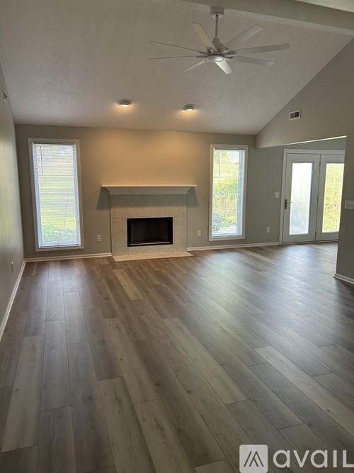 A spacious living room with wood flooring and a fireplace.