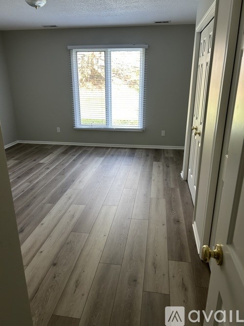 A room with wooden flooring and a window with blinds.