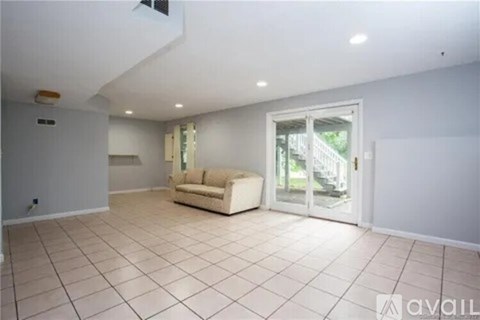 A spacious living room with a couch and a sliding glass door.