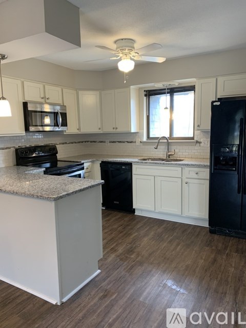 A kitchen with a black fridge and white cabinets.