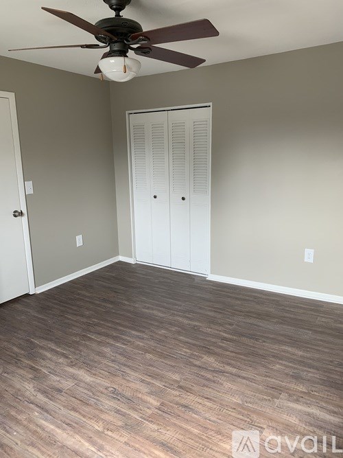 A room with a ceiling fan and wood flooring.