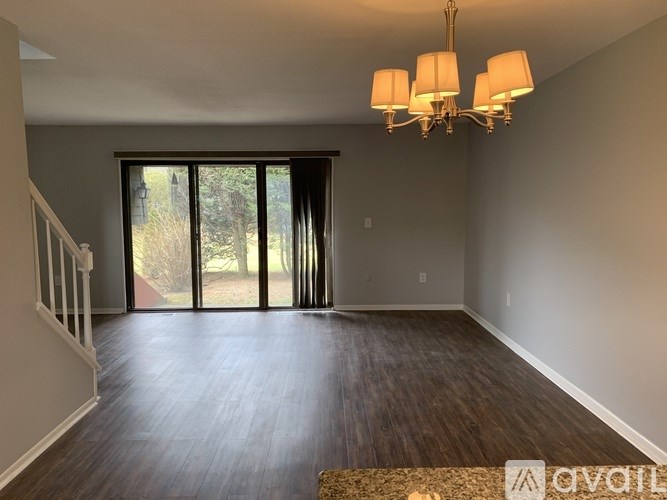 A living room with a chandelier, hardwood floors, and sliding glass doors.