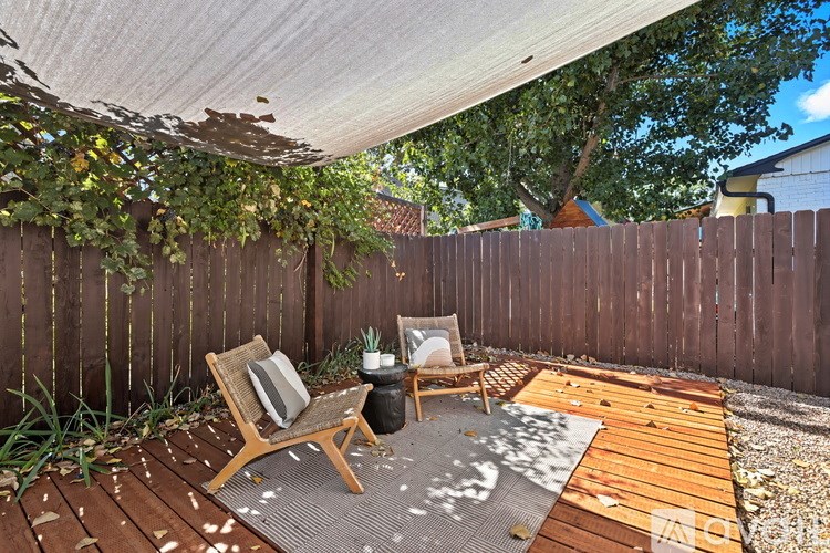 A wooden deck with a chair and a table under a white canopy.