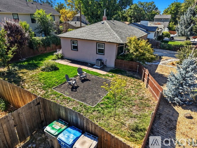 A backyard with a pink house, a wooden fence, and a small tree.
