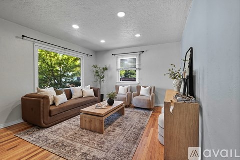 A living room with a brown sofa, a wooden coffee table, and a rug on the floor.