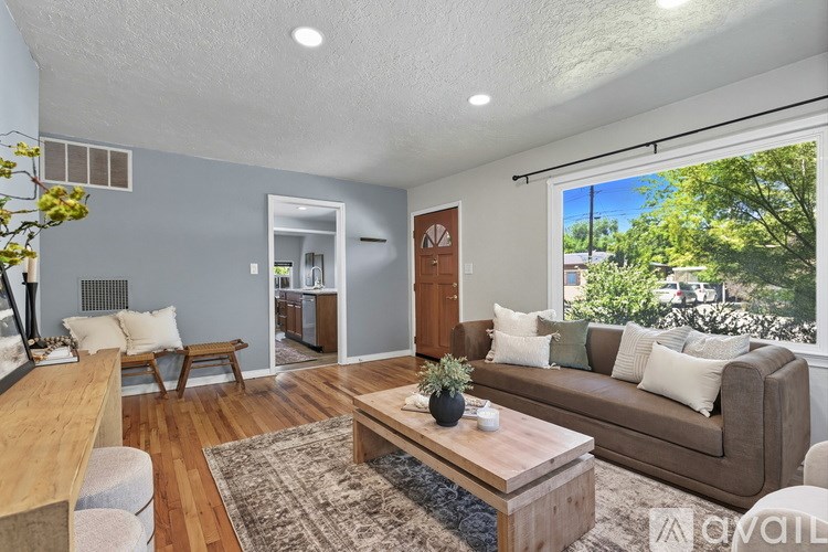 A living room with a brown couch, a coffee table, and a large window.
