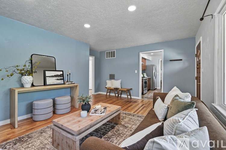 A living room with a brown couch, a wooden coffee table, and a mirror on the wall.