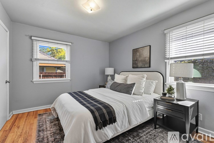 A bedroom with a large bed and a window with blinds.
