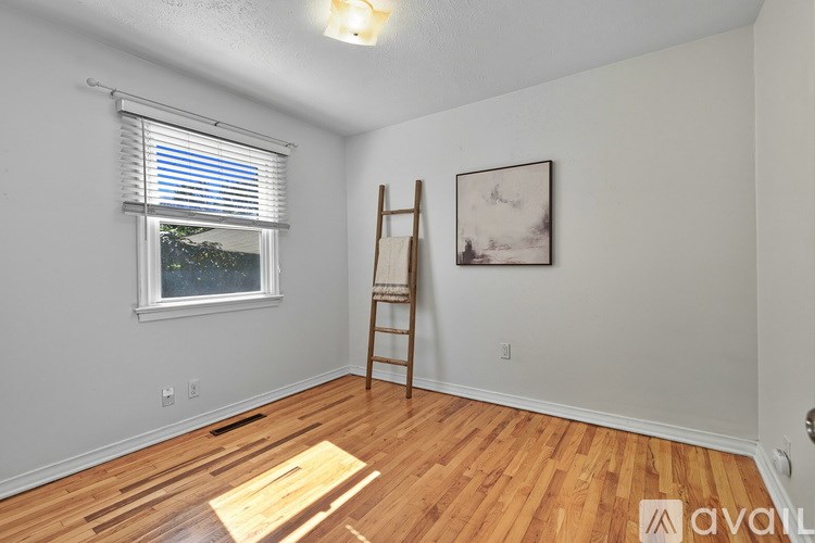 A room with wooden flooring and a ladder against the wall.