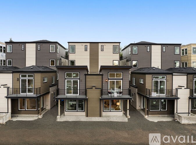 A row of modern townhouses with balconies and a clear blue sky above.