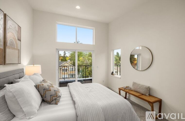 A bedroom with two beds, a bench, and a window overlooking a balcony.