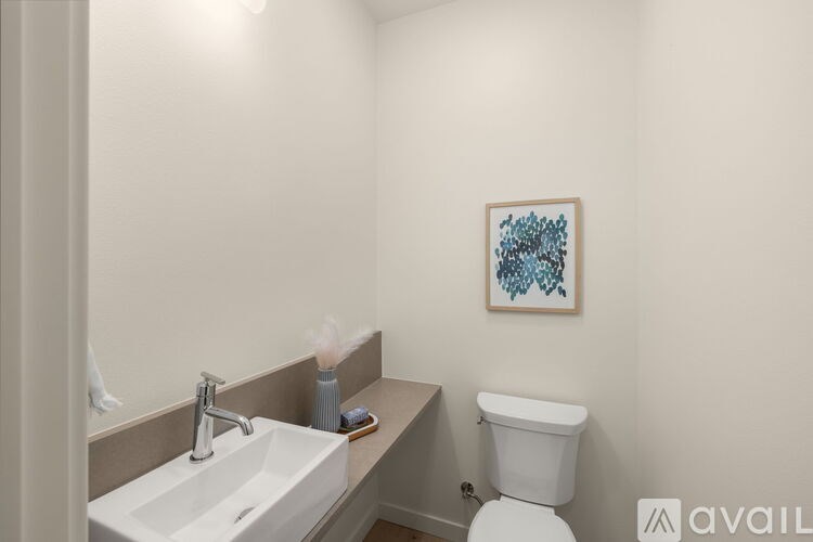 A bathroom with a white toilet, a white sink, and a painting on the wall.
