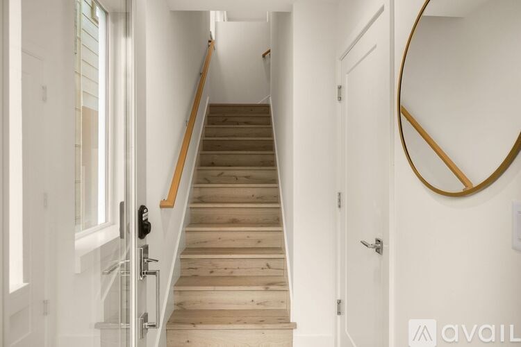 A wooden staircase with a glass railing and a round mirror on the wall.
