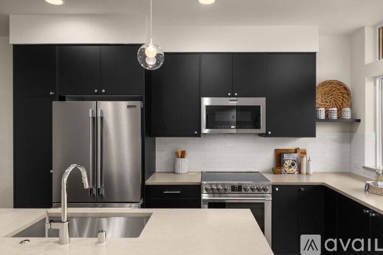 A modern kitchen with black cabinets and stainless steel appliances.