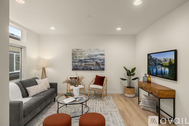 A living room with a grey couch, a coffee table, a chair, a potted plant, and a painting on the wall.