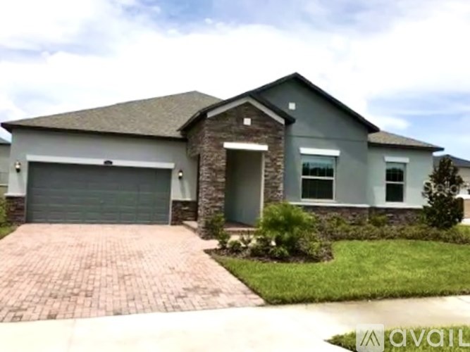 A house with a grey garage door and a brick driveway.