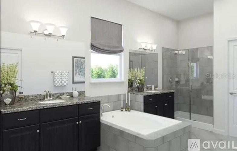 A bathroom with a white tub and black cabinets.