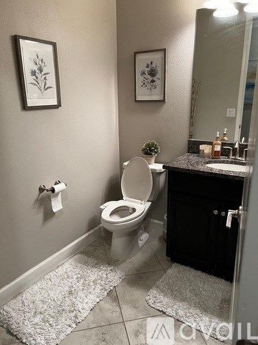 A bathroom with a toilet, sink, and two framed pictures on the wall.
