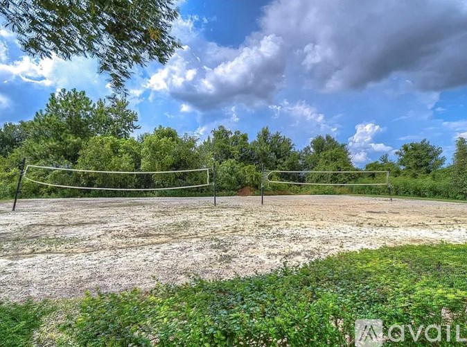 A volleyball net is set up in the middle of a field with trees in the background.