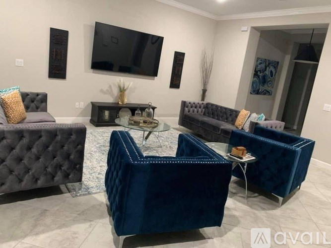 A living room with a grey and blue sofa set, a coffee table, and a flat screen TV mounted on the wall.