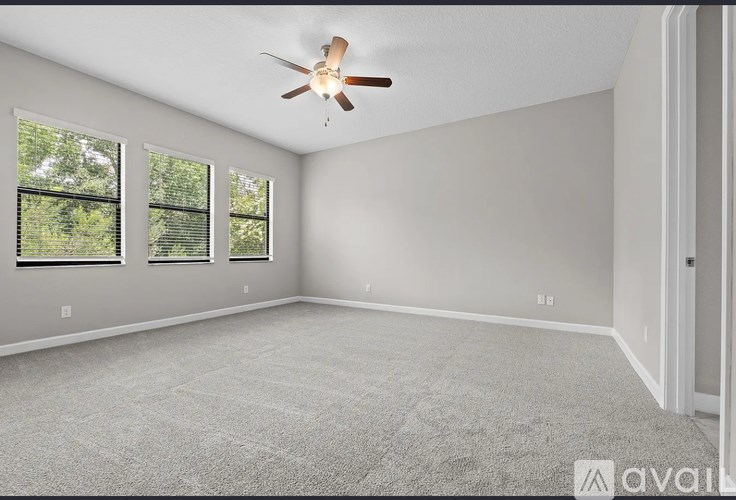 A room with a ceiling fan and three windows.