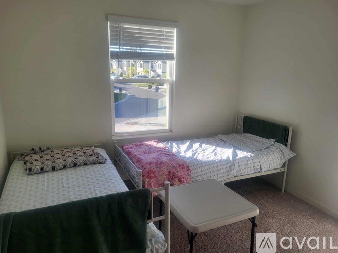A bedroom with two beds and a window overlooking a parking lot.