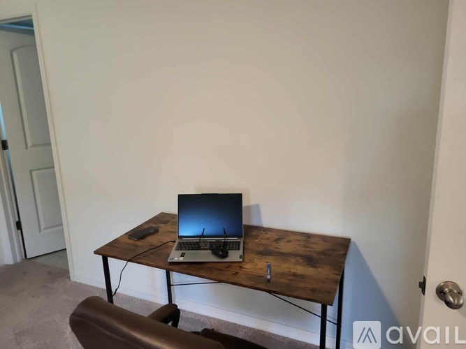 A laptop is on a wooden table with a black mouse and keyboard.