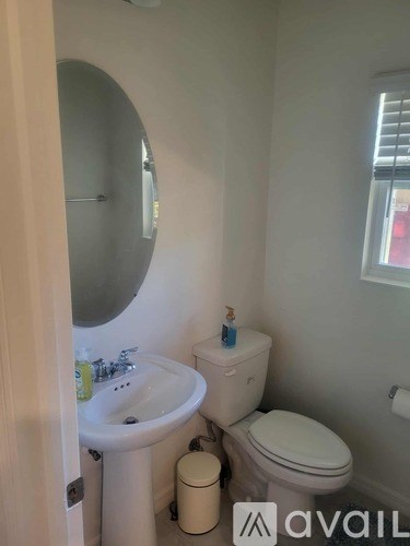 A small bathroom with a toilet, sink and mirror.