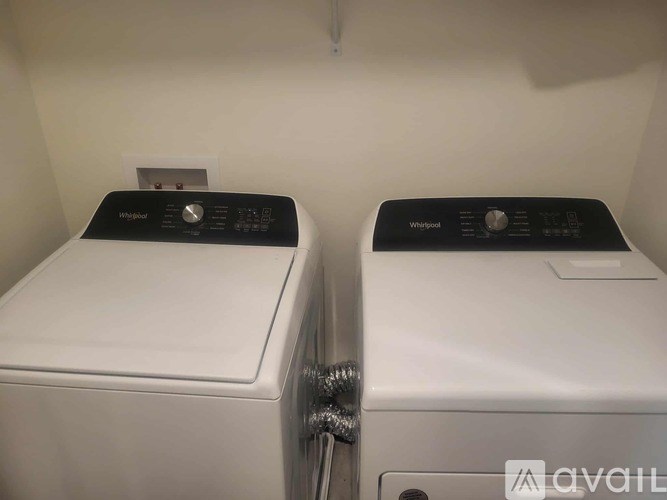 Two white Whirlpool washing machines are side by side.