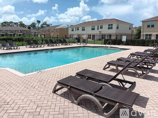 A pool surrounded by sun loungers and chairs.