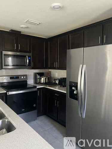 A kitchen with black cabinets and stainless steel appliances.