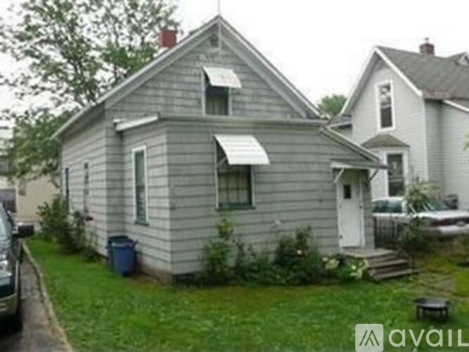 A house with a grey siding and a white awning is shown.