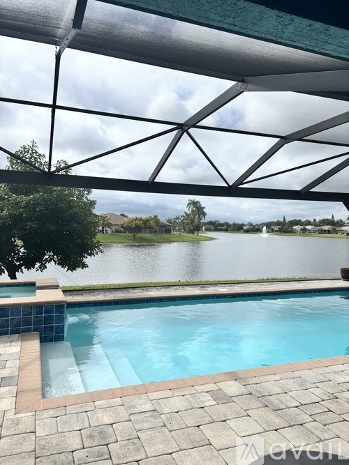 A pool under a black roof with a view of a lake.