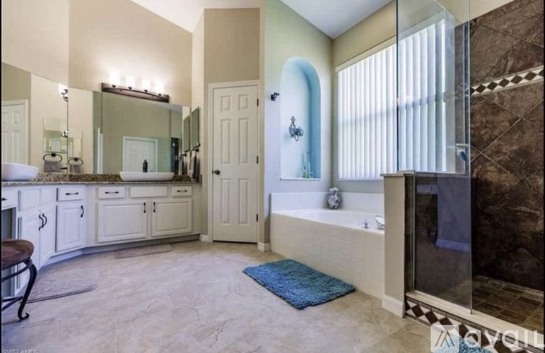 A bathroom with a large mirror, a bathtub, and a sink.