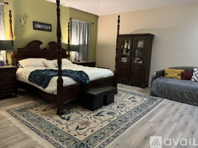 A bedroom with a bed, chair, and ceiling fan.