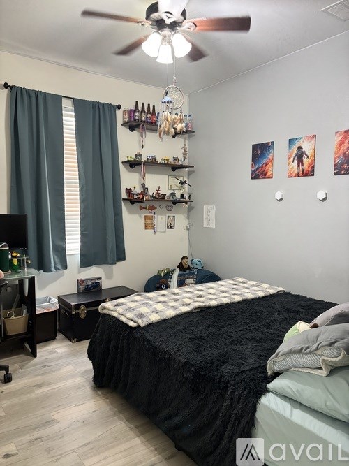 A bedroom with a black bedspread and a ceiling fan.