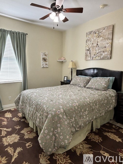 A bedroom with a floral bedspread and a ceiling fan.