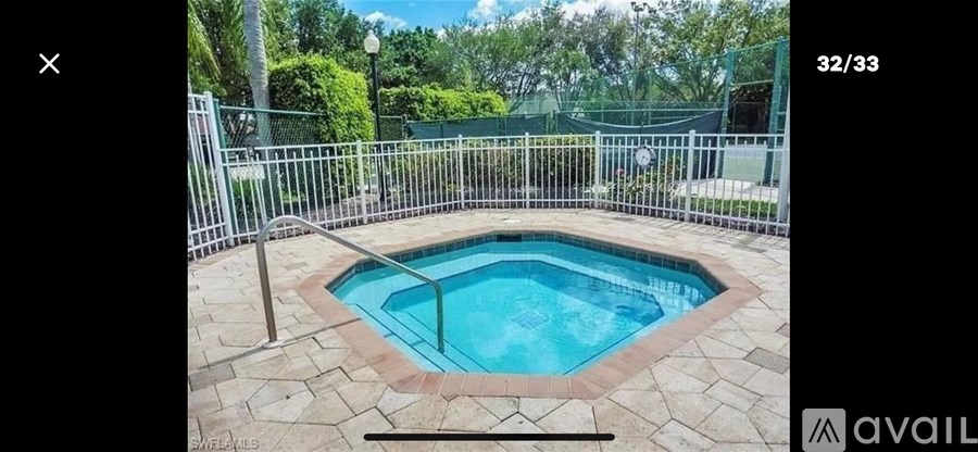 A small pool surrounded by a metal fence and stone tiles.