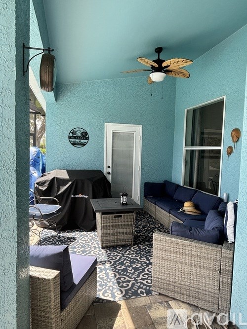A patio with a black umbrella and a blue couch.