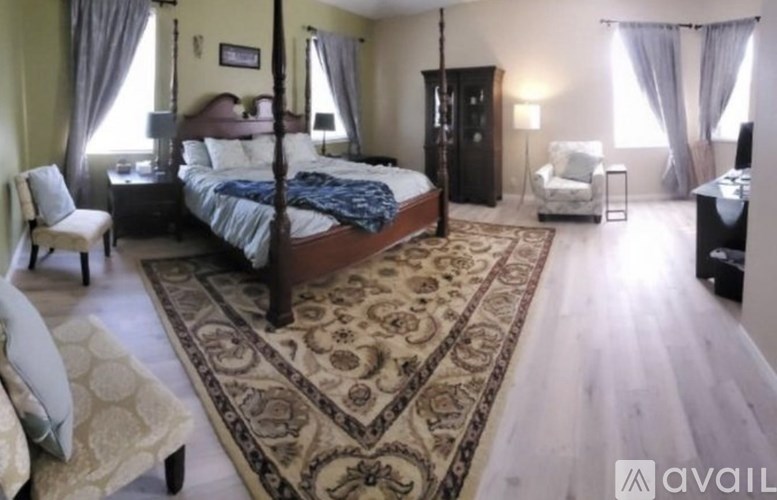 A bedroom with a four poster bed and a rug on the floor.