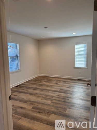 A room with wooden flooring and a door on the right.