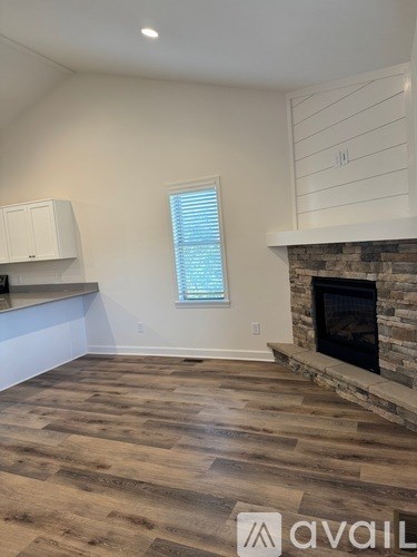 A room with a stone fireplace and wooden flooring.