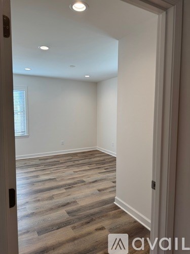 A room with wooden flooring and a door on the left.
