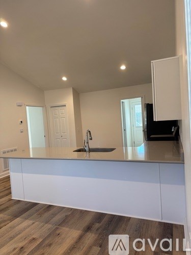 A kitchen with white cabinets and a wooden floor.